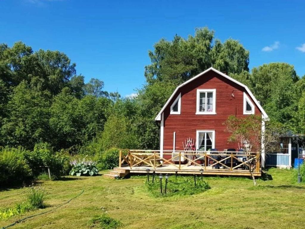 a red house with a deck in a yard at Holiday home RAMSJÖ II in Ramsjö