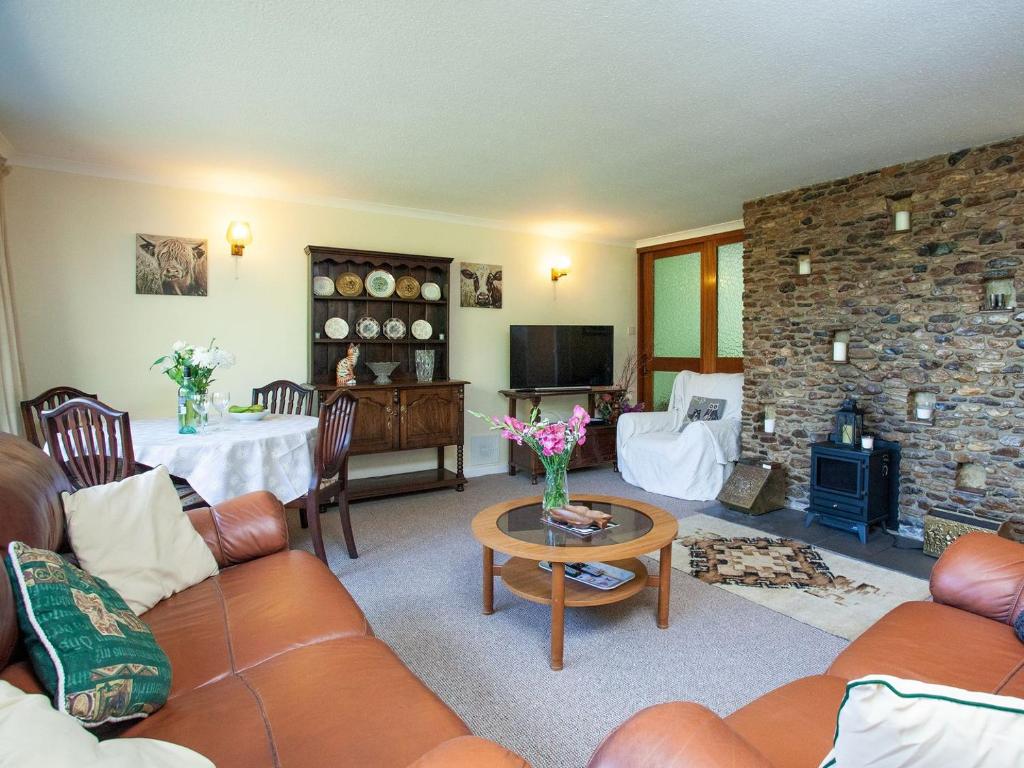 a living room with a couch and a stone fireplace at Purlbridge Bungalow in Southleigh