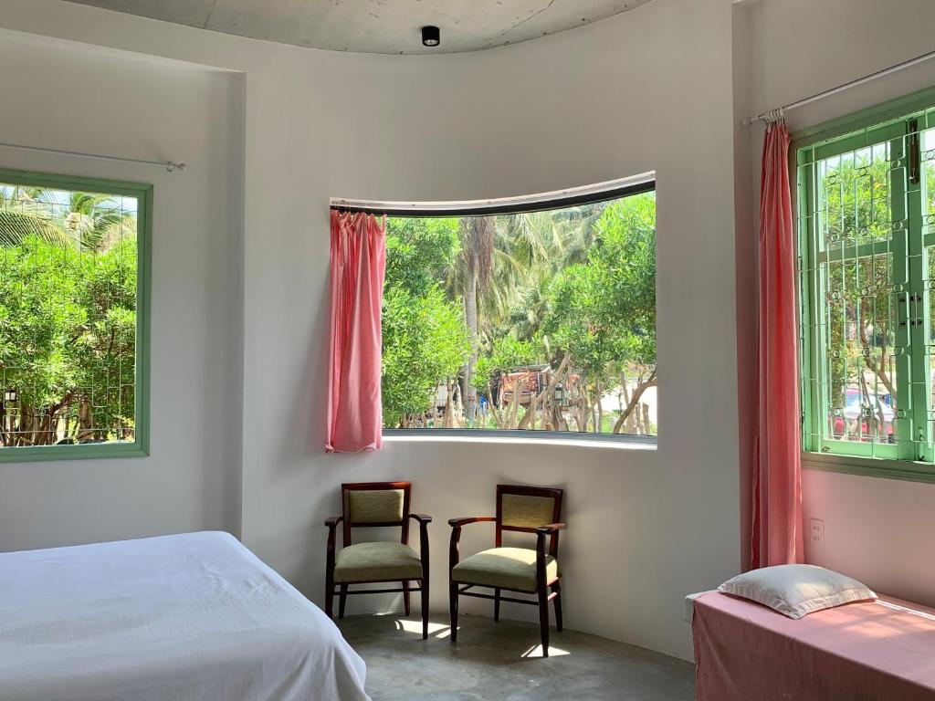 a bedroom with two chairs and a bed and a window at Chành Rành House in Vĩnh Hy