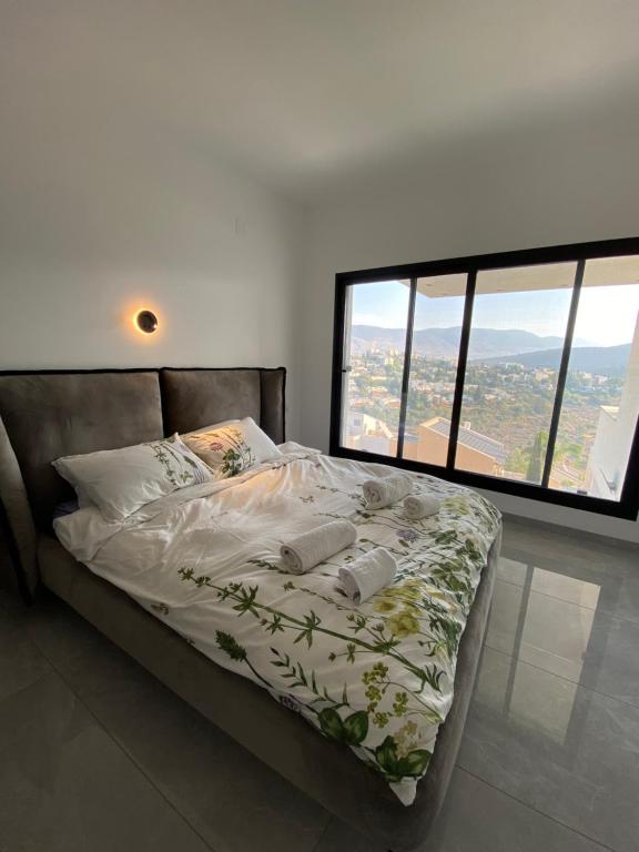 a bed in a room with a large window at studio ilanit in Karmiel