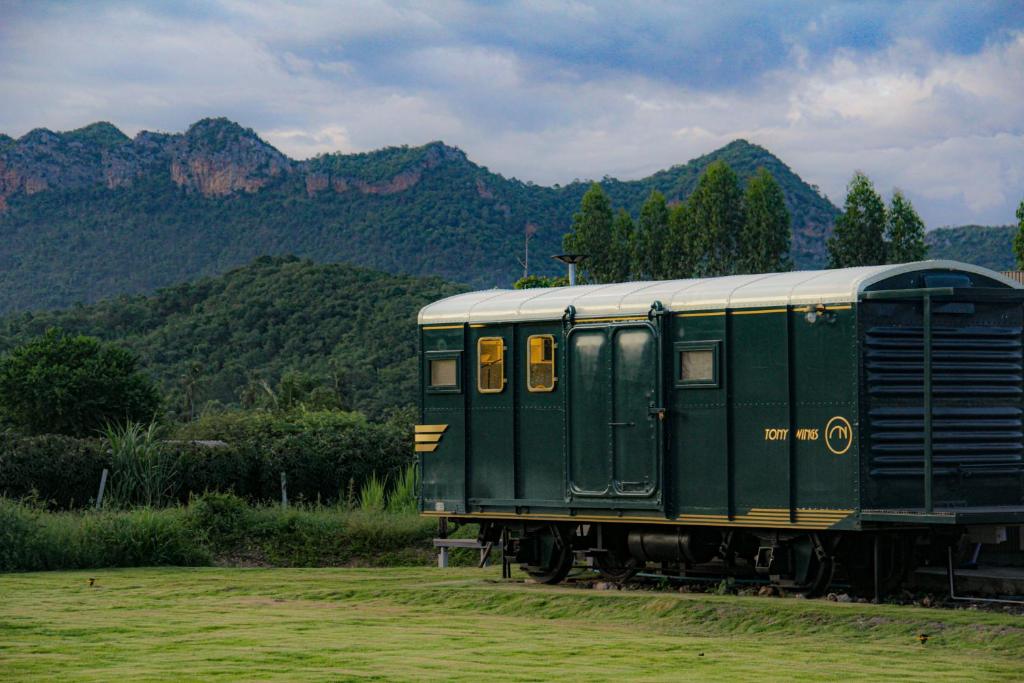 a green train car on the tracks with mountains in the background at Nex Station Kanchanaburi in Kanchanaburi