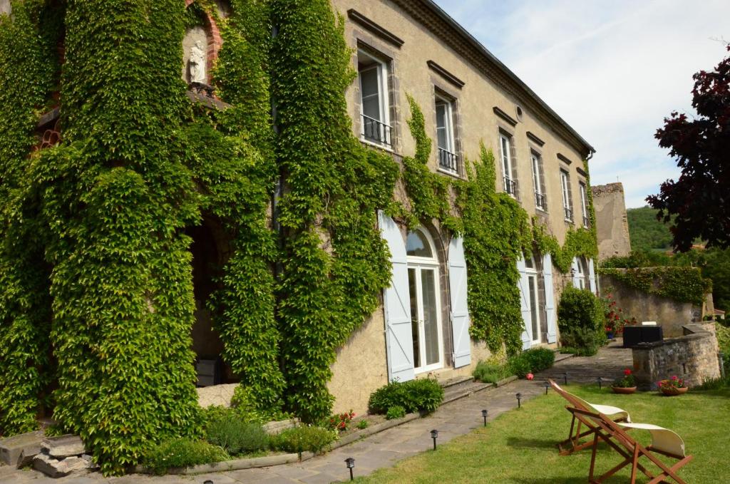 an ivy covered building with a bench in front of it at La Lit'Hote in Mirefleurs