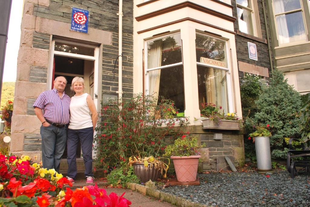 a man and a woman standing outside of a house at Laurel Bank Guest House in Keswick