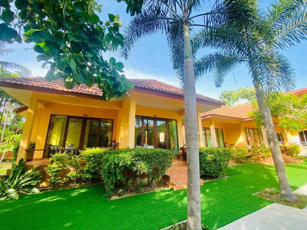 a house with a green lawn in front of it at Pranmanee Beach Resort in Sam Roi Yot