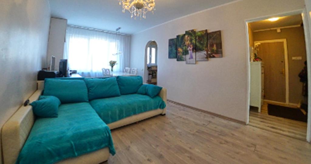 una sala de estar con un sofá azul en una habitación en Spilves 35, en Riga