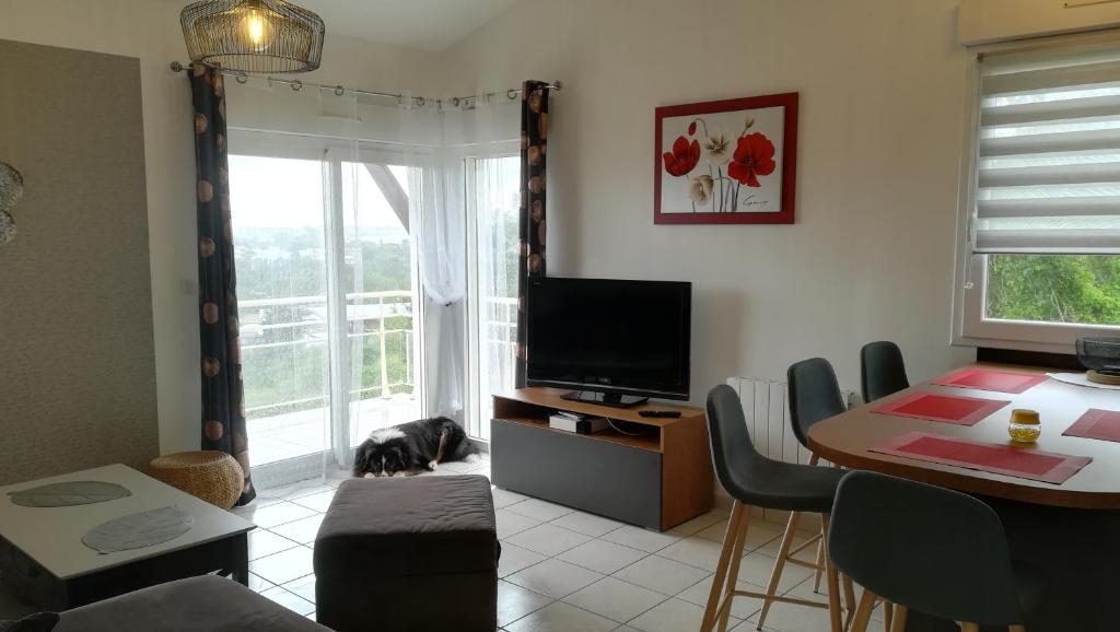 a living room with a tv and a table with a dog at L Hibiscus in Jonzac