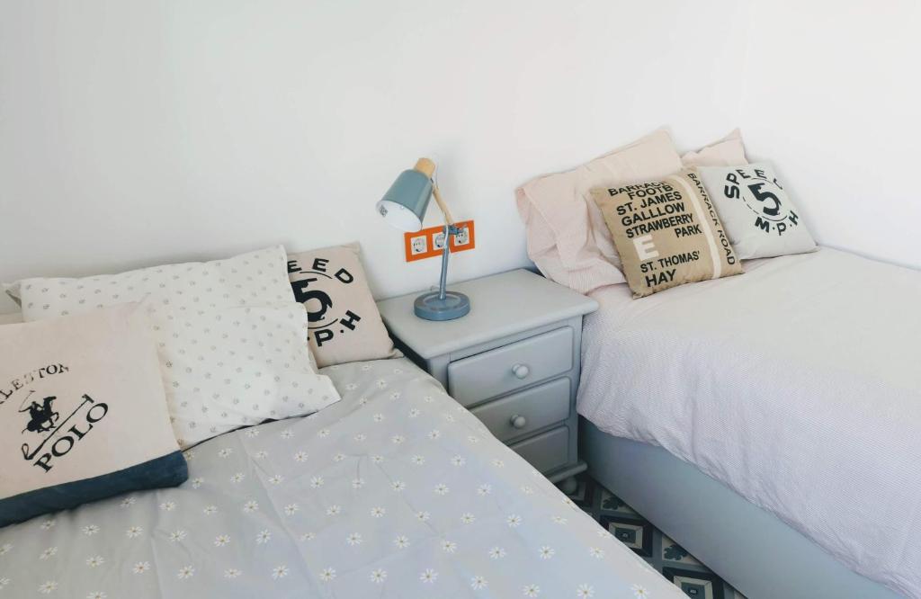 a bedroom with two beds with pillows and a night stand at ABA DALÍ in Conil de la Frontera