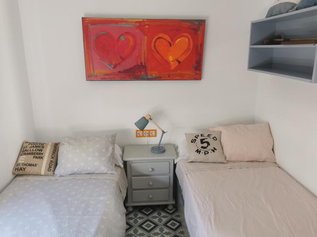 a bedroom with two beds and a painting on the wall at ABA DALÍ in Conil de la Frontera