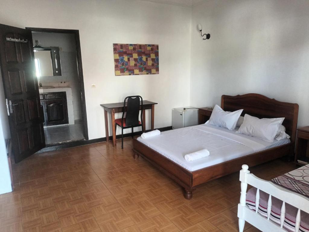 Un dormitorio con una cama y una mesa con una silla. en LOTUS HOTEL, en Antsiranana
