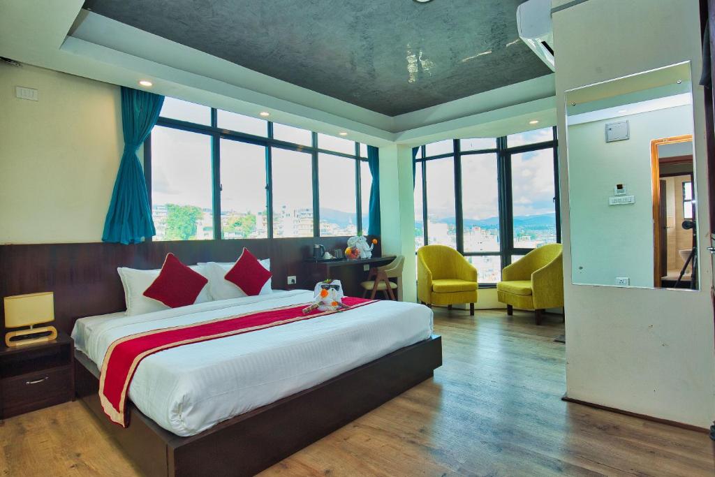 Hotel Grand View في كاتماندو: غرفة نوم بسرير كبير في غرفة بها نوافذ