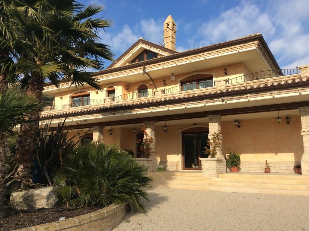 a building with a palm tree in front of it at Villa Civita in Colonnella