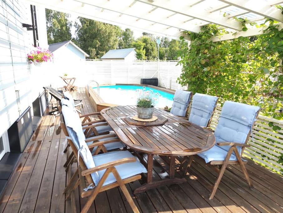 a deck with a table and chairs next to a pool at Yksityinen kellarikerros omalla sisäänkäynnillä, Pietarsaari in Pietarsaari