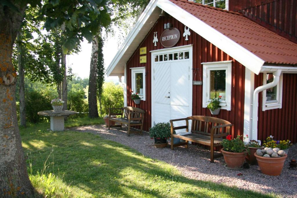 un banco sentado fuera de un edificio rojo en Hornborgasjöns Stugby, en Bjällum