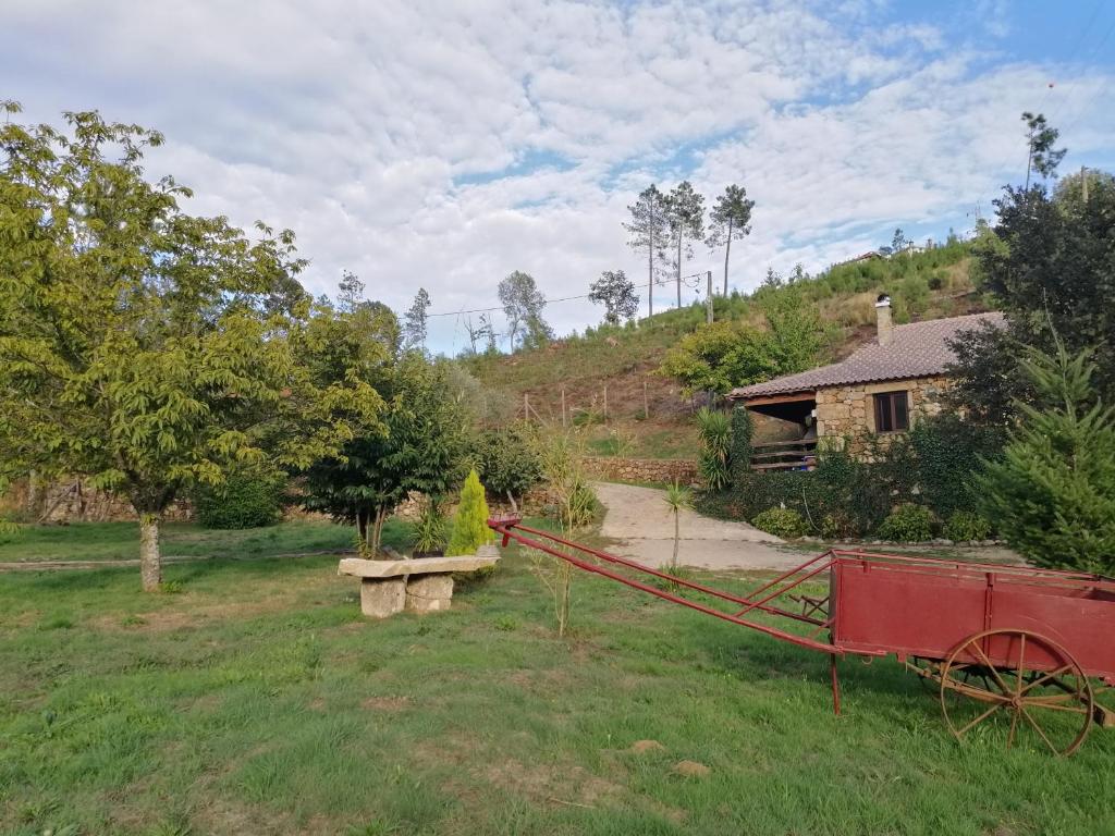 a red cart in a yard with a house at Quinta do Pé Longo - Serra da Estrela in Cortes do Meio