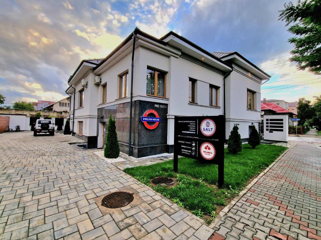 a white house with a sign in front of it at English House in Bistriţa