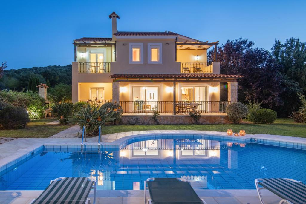 a villa with a swimming pool in front of a house at Gerani Villas in Gerani