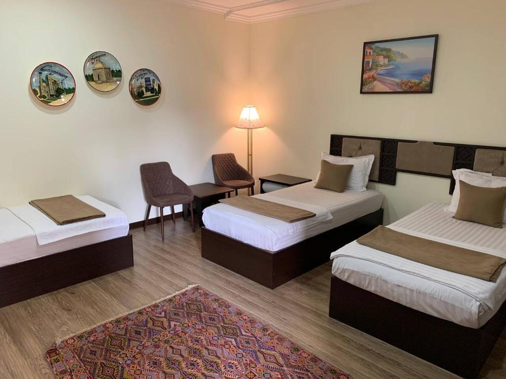 a hotel room with two beds and a table and chairs at CRYSTAL HOTEL in Bukhara