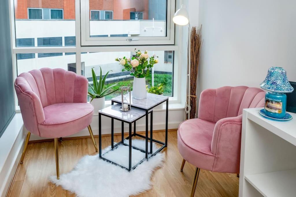two pink chairs and a table in a living room at Central Gunwharf Quays Two Bedroom apartment in Portsmouth