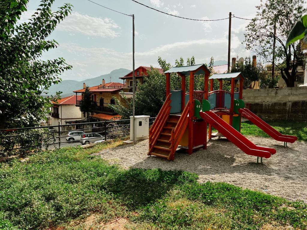 a playground with a red slide in a yard at Elena Guesthouse in Kalabaka
