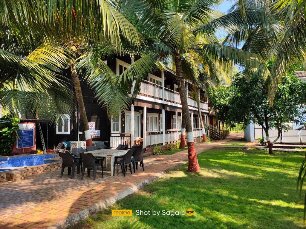 una mesa y sillas frente a un edificio con palmeras en Casa Seaesta Beach Cottages and Suites, en Arambol