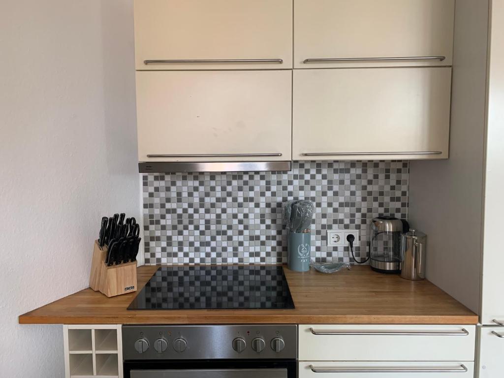 uma cozinha com armários brancos e um forno com placa de fogão em L8 Street - Monteurwohnung - Zähringerstr em Karlsruhe