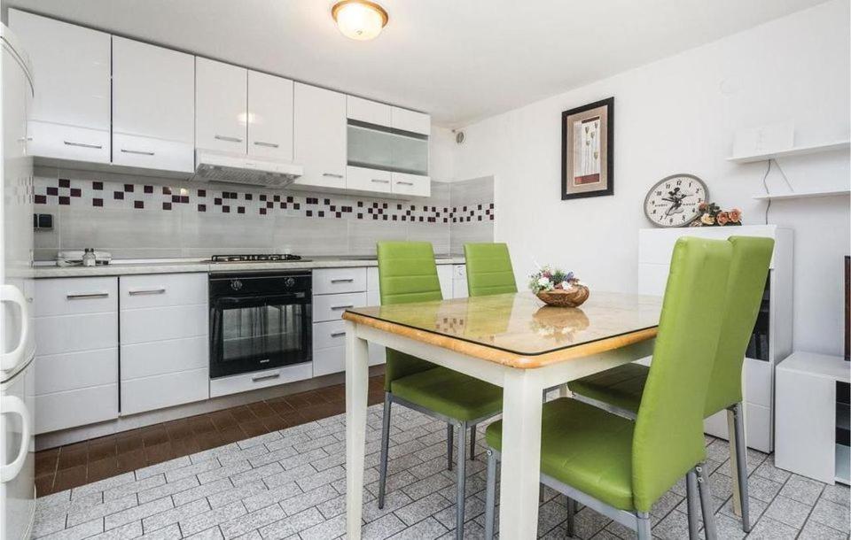 une cuisine avec une table en bois et des chaises vertes dans l'établissement Apartmani L&Z, à Petrčane