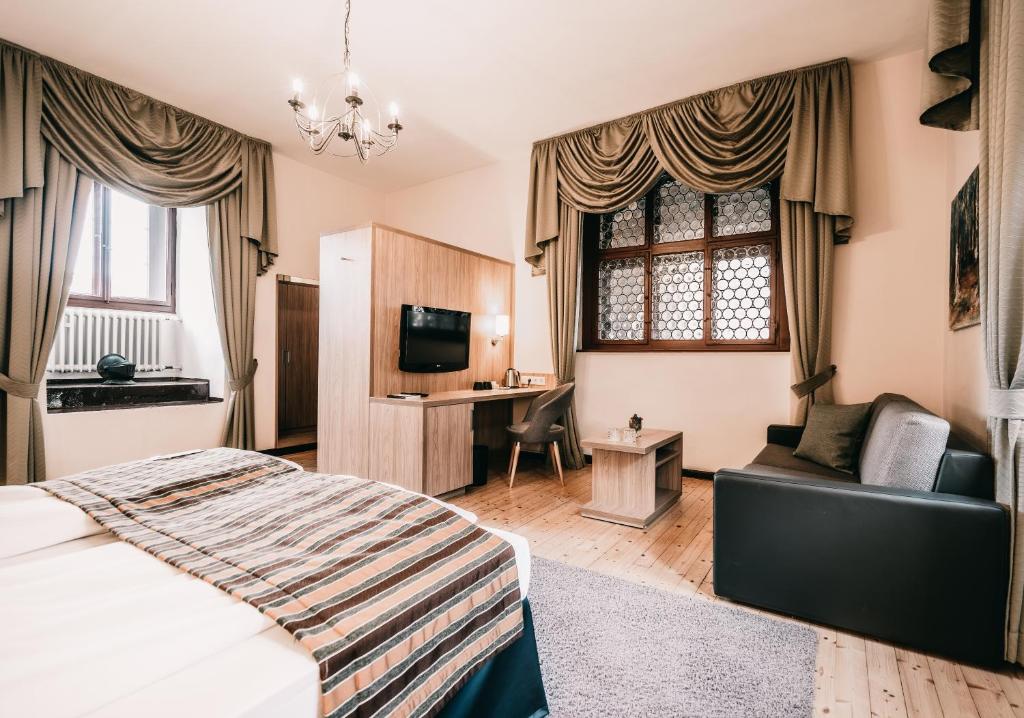 ein Schlafzimmer mit einem Bett, einem Sofa und einem Schreibtisch in der Unterkunft Romantik Hotel Schloss Hohenstein in Ahorn