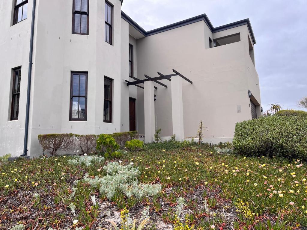 a white house with a lot of flowers in front of it at Jambase Seaside House in Big Bay