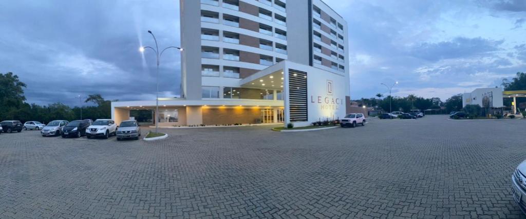 un gran edificio con coches estacionados en un estacionamiento en Legacy Hotel Guaratinguetá - Ao lado de Aparecida -SP, en Guaratinguetá