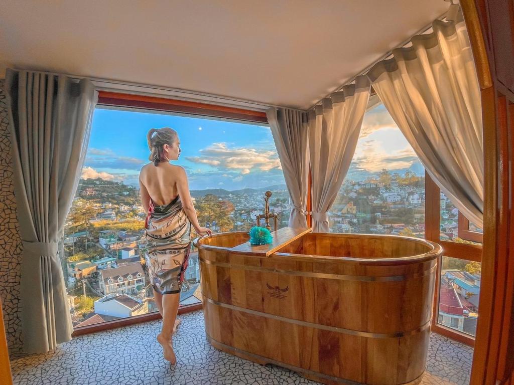 una donna in piedi in una vasca da bagno in una stanza con finestra di Casanova Dalat Hotel a Da Lat