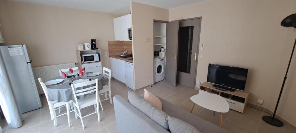uma sala de estar com um sofá, uma mesa e uma cozinha em Appart T2 standing tout confort avec balcon - parking en option em Lyon