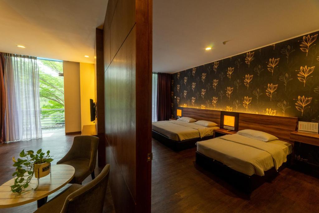 a hotel room with two beds and a table at Waterfront Boutique Hotel in Port Dickson