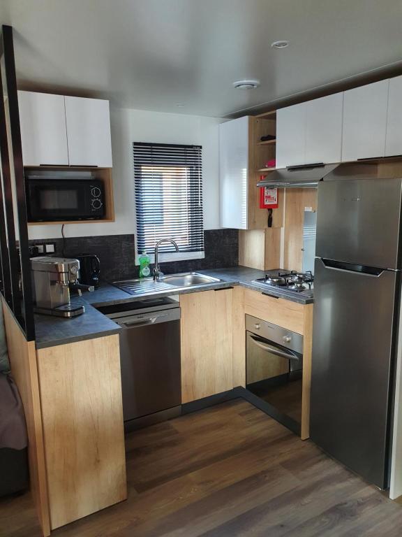 a kitchen with stainless steel appliances and wooden cabinets at Mobilhome camping le MAR ESTANG in Canet-en-Roussillon