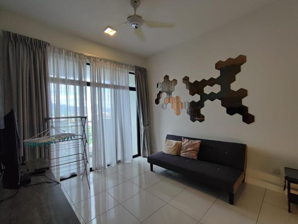 a living room with a black couch and a television at Mint Cabin @ Oasis Condo Ipoh in Ipoh