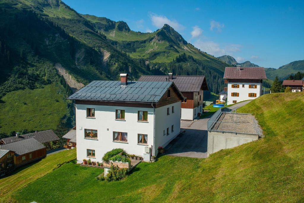 una casa blanca en una colina con montañas en el fondo en Haus Furka, en Damüls