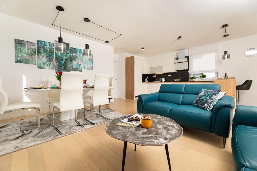 Una sala de estar con un sofá azul y una mesa. en Sun Residence Krk, en Krk
