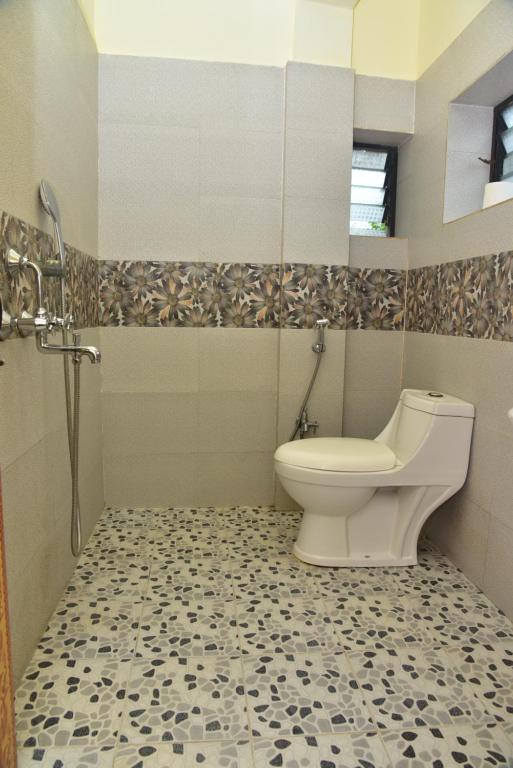 a bathroom with a toilet and a tiled floor at Jardim a Mar in Agonda