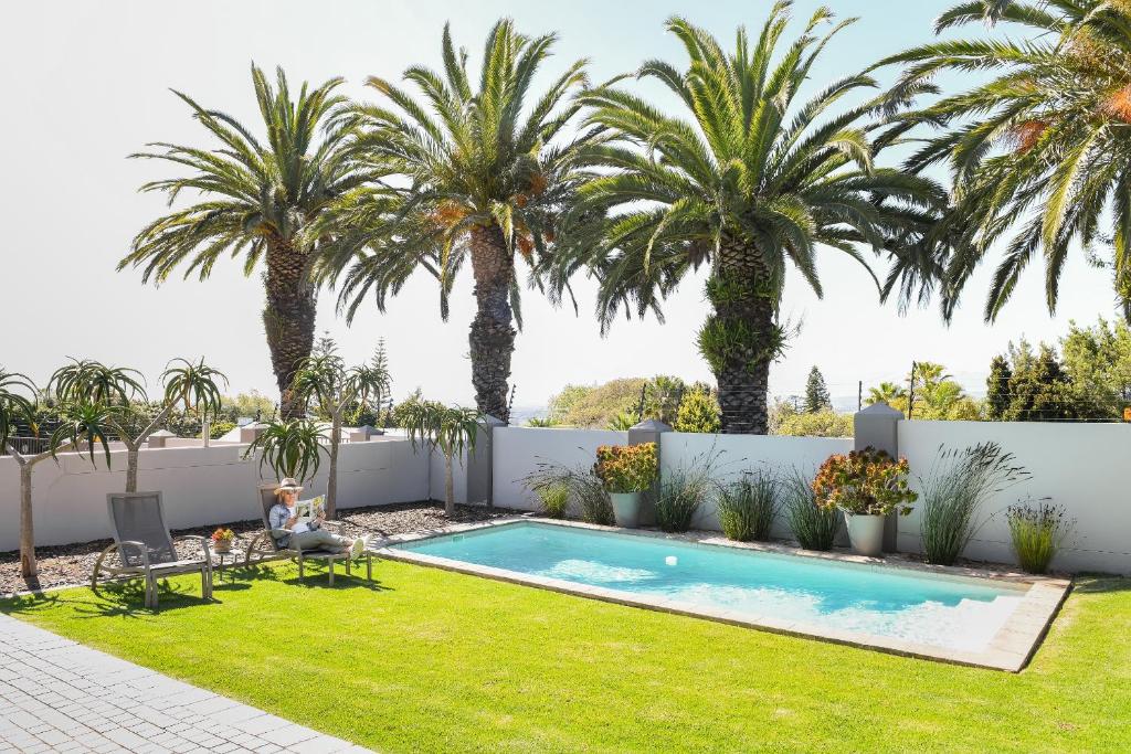 a backyard with a swimming pool and palm trees at Four Palms Accommodation in Durbanville