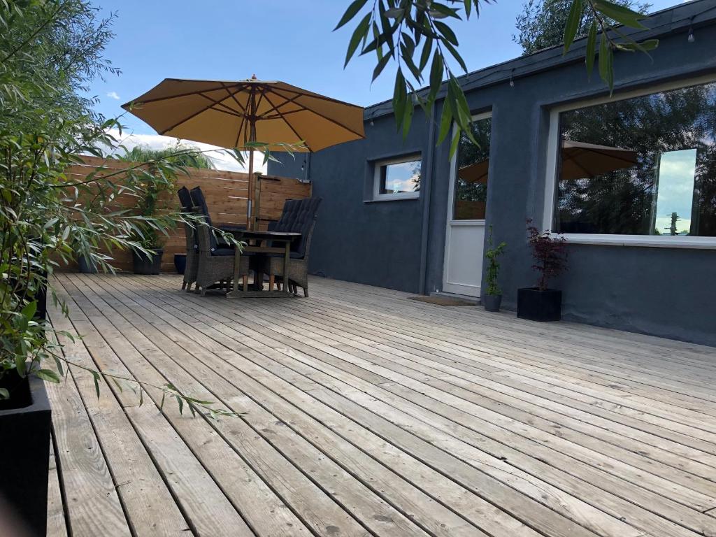 a wooden deck with a table and an umbrella at L Antre Vous in Mons