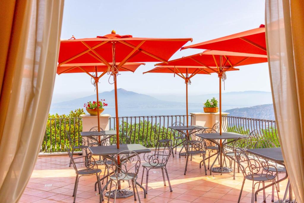eine Gruppe von Tischen und Stühlen mit Sonnenschirmen auf einem Balkon in der Unterkunft Grand Hotel Hermitage in SantʼAgata sui Due Golfi