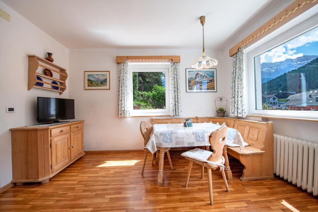 uma sala de jantar com uma mesa e uma televisão em Apartments Vintlana em Wolkenstein