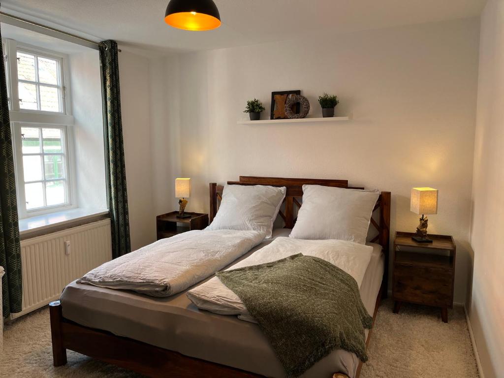 a bedroom with a bed with two lamps and a window at Lykkefund - Ferienwohnungen in Hafennähe in Glückstadt