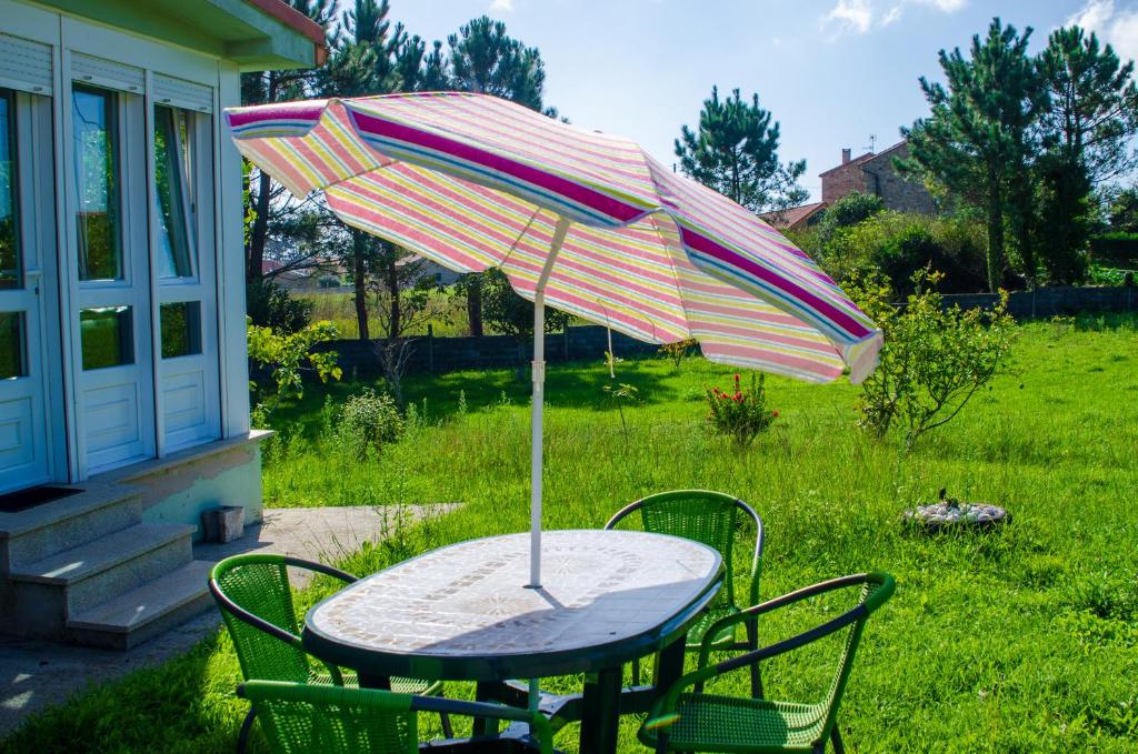 una mesa con sombrilla en un patio en Casa Frutales Escaselas, en Finisterre