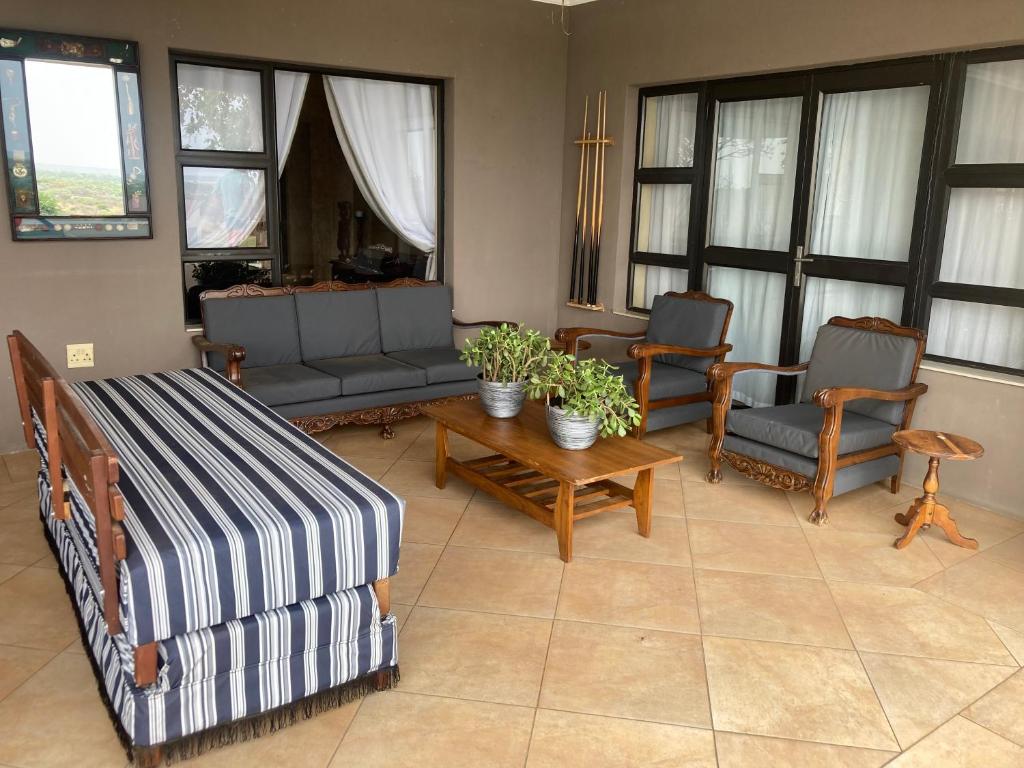 a living room with a bed and chairs and windows at Euphoria Self Catering Home in Naboomspruit