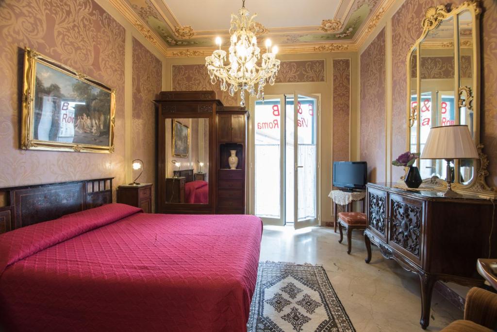 a bedroom with a red bed and a chandelier at B&B Via Roma in Marsala