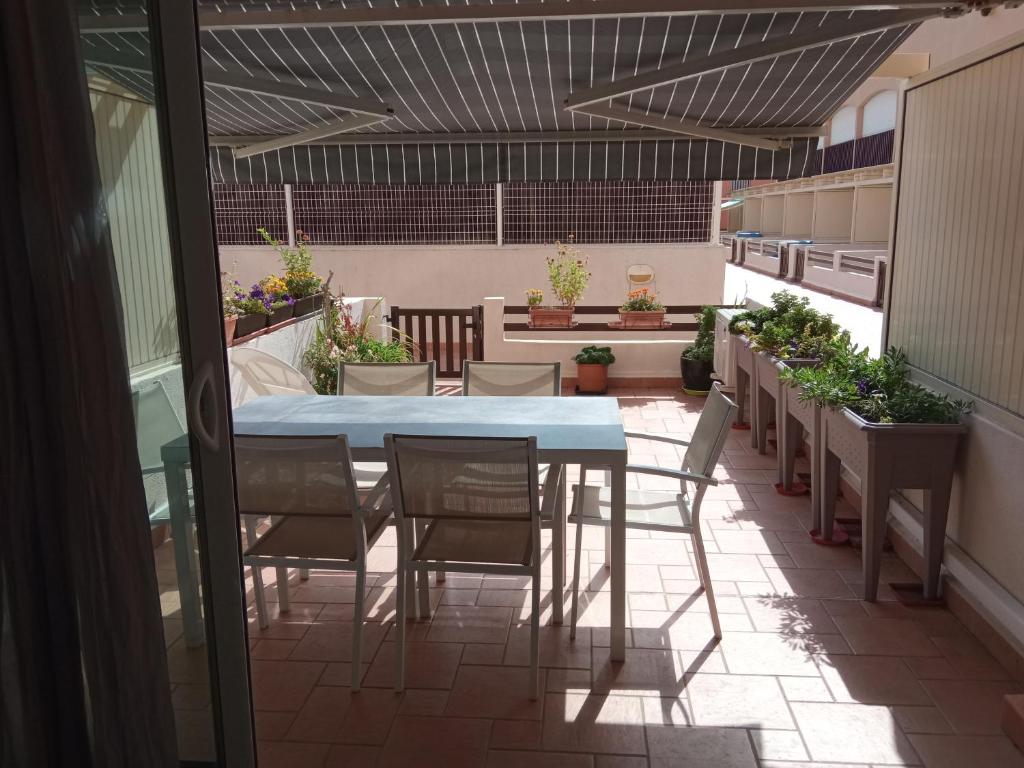 un patio con mesa, sillas y macetas en Residence Saint Clair - Studio Elena, en Cap d'Agde