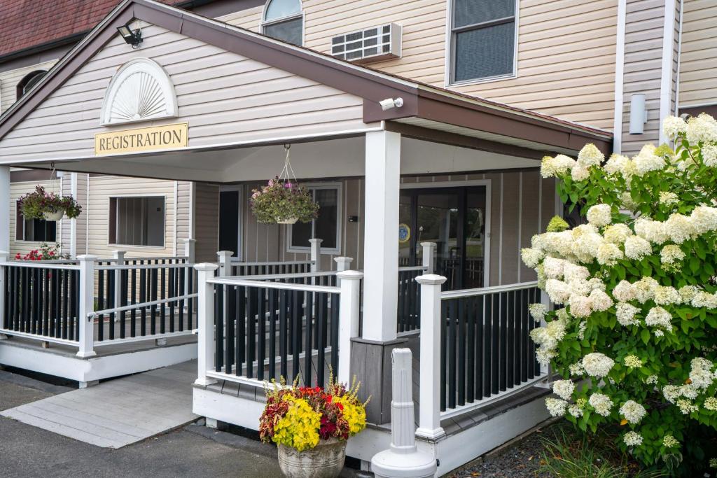 - une terrasse couverte à l'avant d'une maison fleurie dans l'établissement All Seasons Inn & Suites, à Bourne