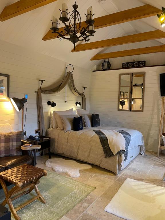 a bedroom with a large bed and a chandelier at Charming stone Bothy at Loch Lomond in Luss