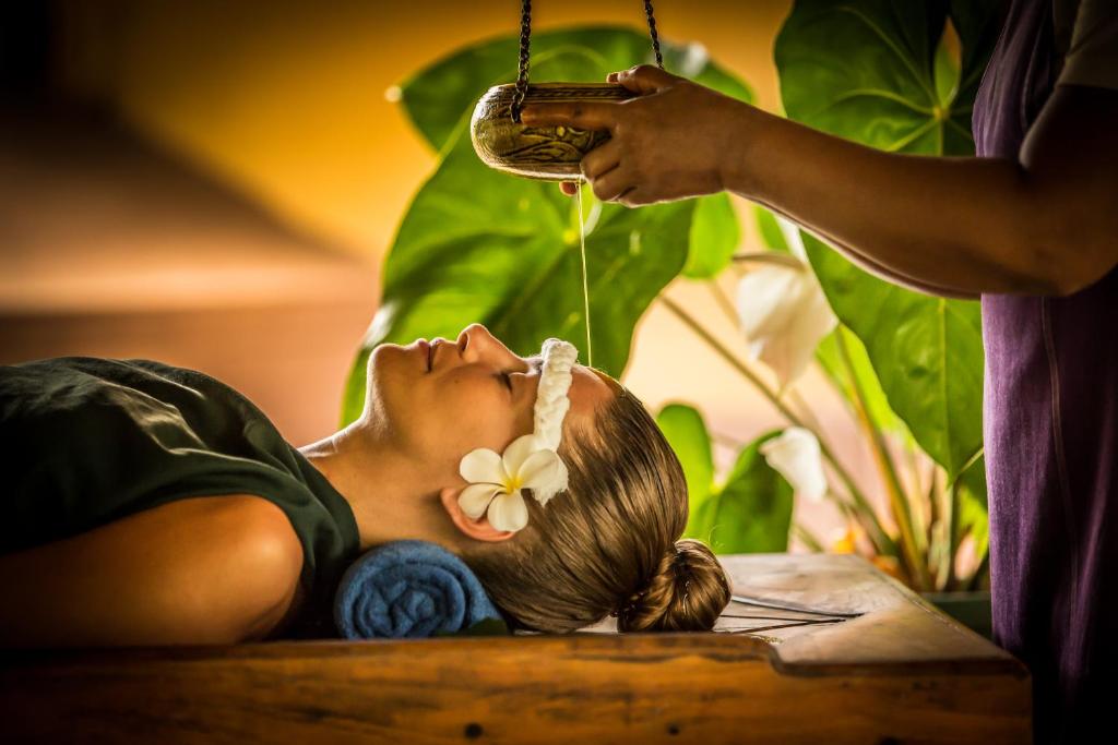 a woman is laying on a table drinking from a bottle at Ayurveda Paradise Maho in Yapahuwa