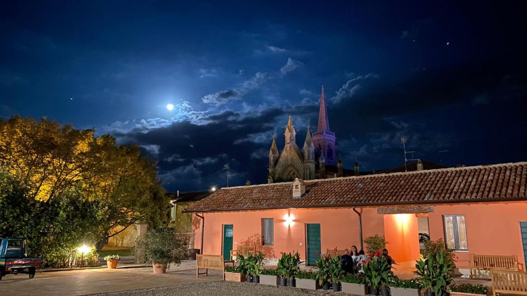 una vista notturna di un edificio e di una chiesa di Agriturismo Pizzavacca a Villanova sullʼArda